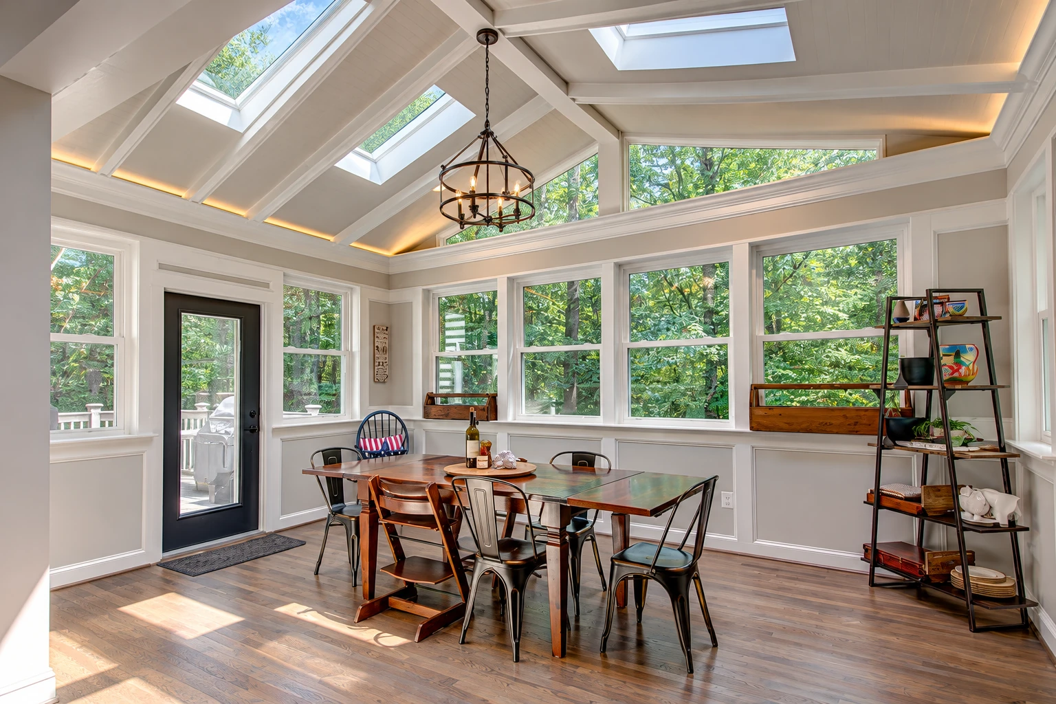 Sunroom dining area with a vaulted skylight roof, large windows, and a wood table surrounded by chairs.